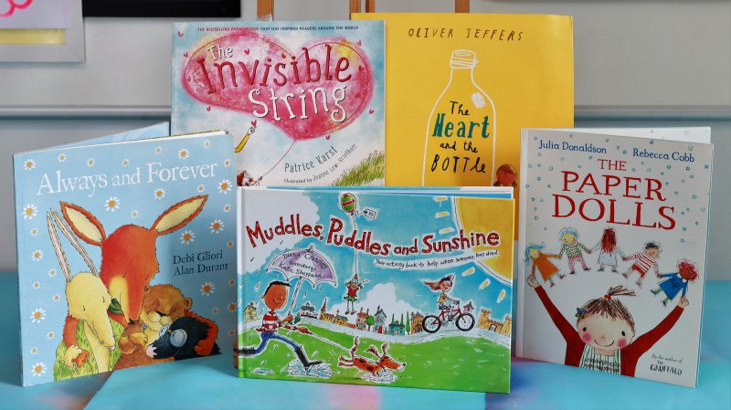 Five children’s books displayed upright on a blue surface, recommended for supporting bereaved children.