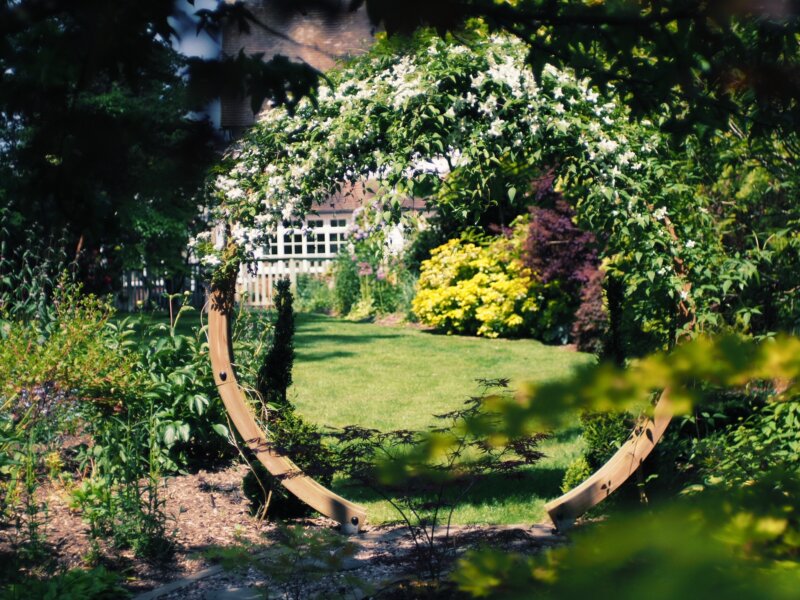 A view of a circular framework covered in flowers in a decorative garden