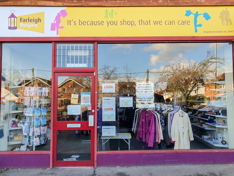 Front view of a charity shop for Farleigh Hospice, featuring a colorful sign that reads 
