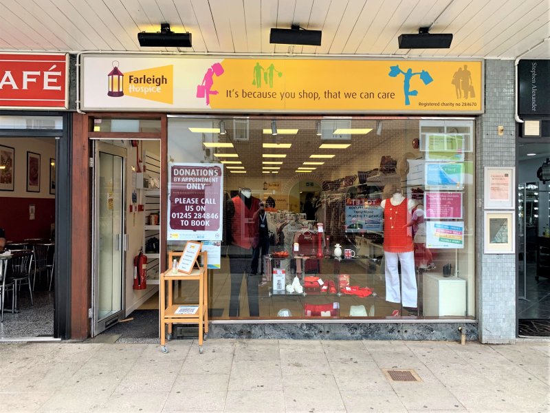 Front view of Farleigh Hospice charity shop showcasing clothing and donation information, promoting community support and charity.