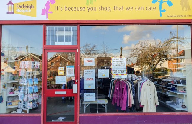 Front view of a Farleigh Hospice charity shop with clothing rails and donated goods displayed inside