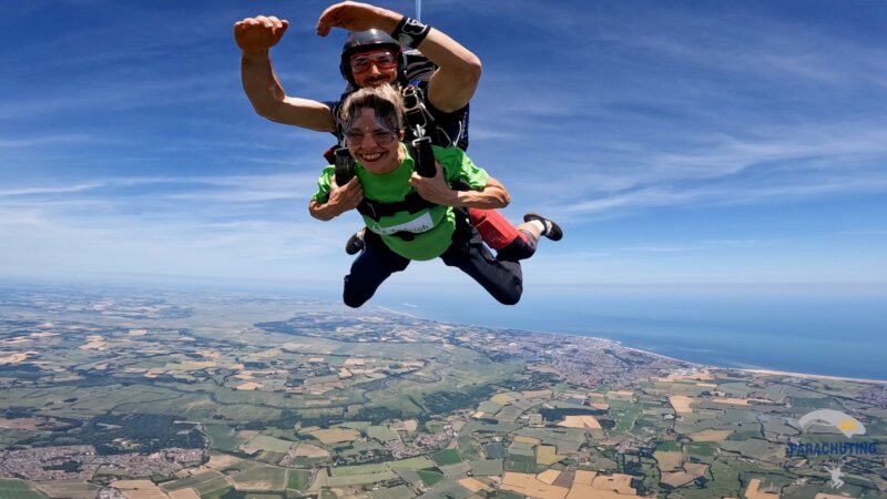 A female skydiver freefalls attached to the male instructor