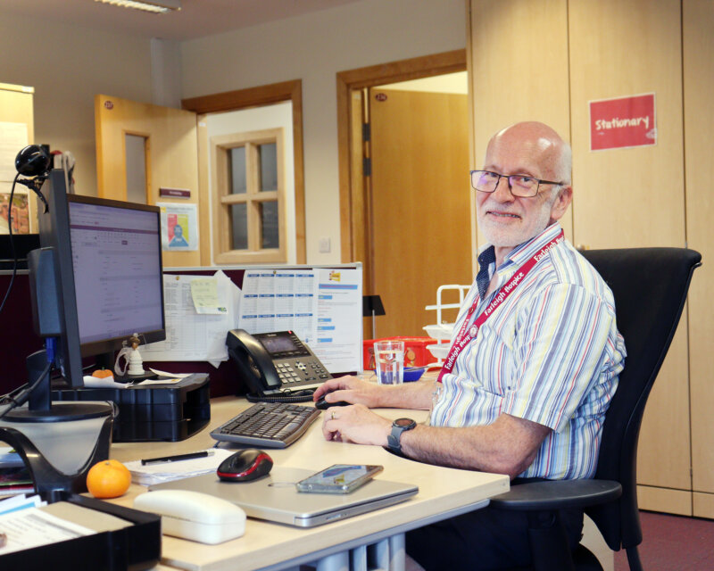 A man in his 60s sits at a desk looking at a computer