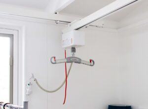 A ceiling-mounted patient lift system with a horizontal track and lifting mechanism.