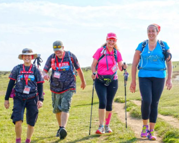 A mixed group of four hikers on the cliff top path in the sunshine