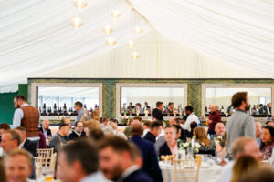 A wide view of a group of people enjoying a meal in a hospitality marquee
