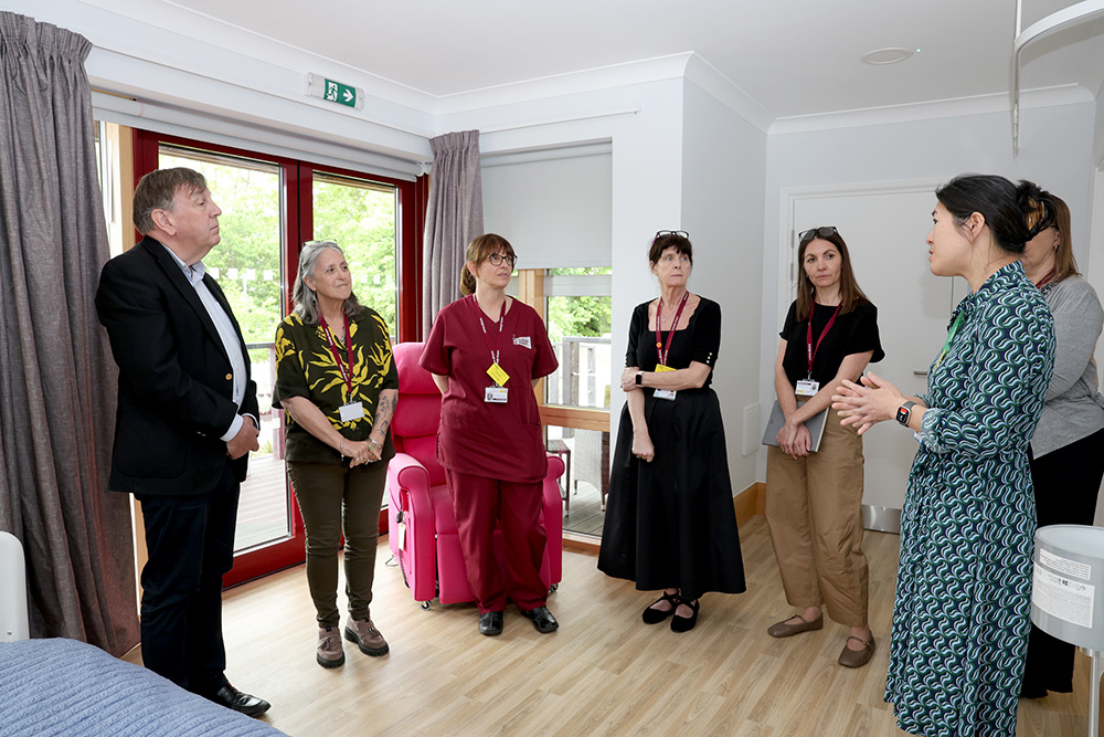 Sir John Whittingdale MP speaks a group of six female members of Farleigh Hospice staff in an Inpatient Unit bedroom