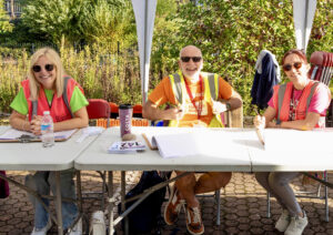 Three volunteers sit behind a registration desk ready to book cyclists onto the ride